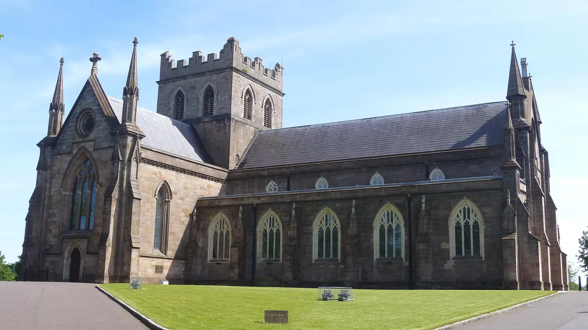 The sandstone Church of Ireland cathedral in Armagh with its square tower, behind a green lawn