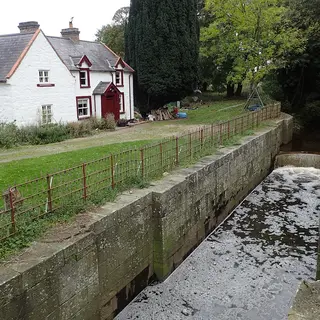 The stone chamber of Moneypenny's Lock with the whitewashed lock-keeper's house beside it