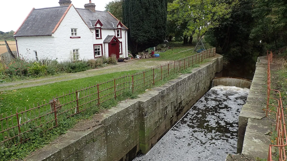The stone chamber of Moneypenny's Lock with the whitewashed lock-keeper's house beside it