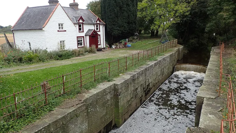 The stone chamber of Moneypenny's Lock with the whitewashed lock-keeper's house beside it