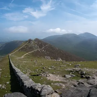 The dry stone Mourne Wall climbing a rocky ridge on Slieve Bearnagh, with the Mourne peaks beyond