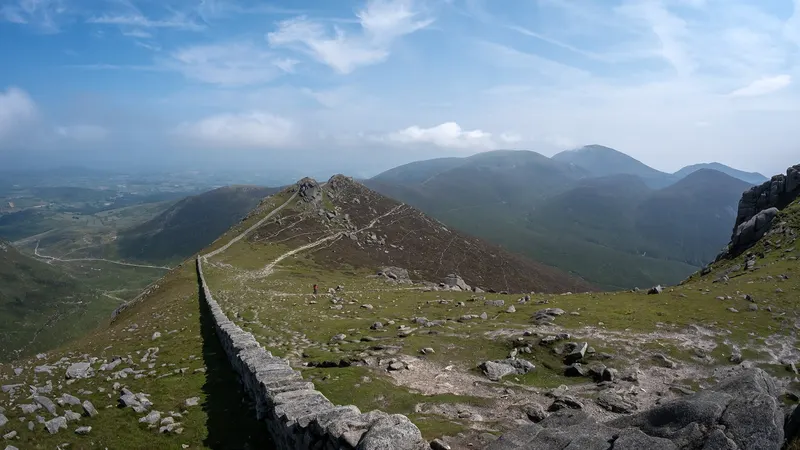 The dry stone Mourne Wall climbing a rocky ridge on Slieve Bearnagh, with the Mourne peaks beyond