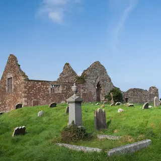 The roofless gables of Bonamargy Friary above a graveyard of old headstones