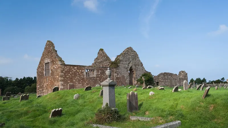 The roofless gables of Bonamargy Friary above a graveyard of old headstones