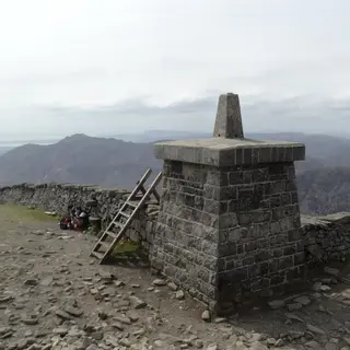 The stone summit tower and cairn on Slieve Donard, with the Mourne Wall and the hills behind