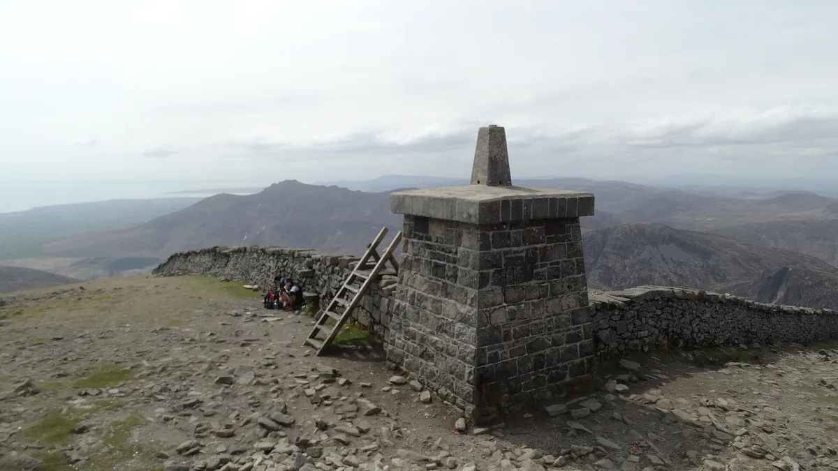 The stone summit tower and cairn on Slieve Donard, with the Mourne Wall and the hills behind