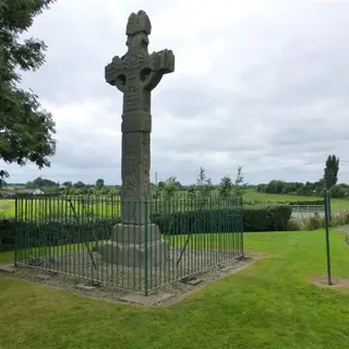 The tall carved high cross at Ardboe inside a low railing on a green