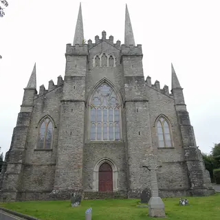The grey stone west front of Down Cathedral with its pinnacles and a large pointed window