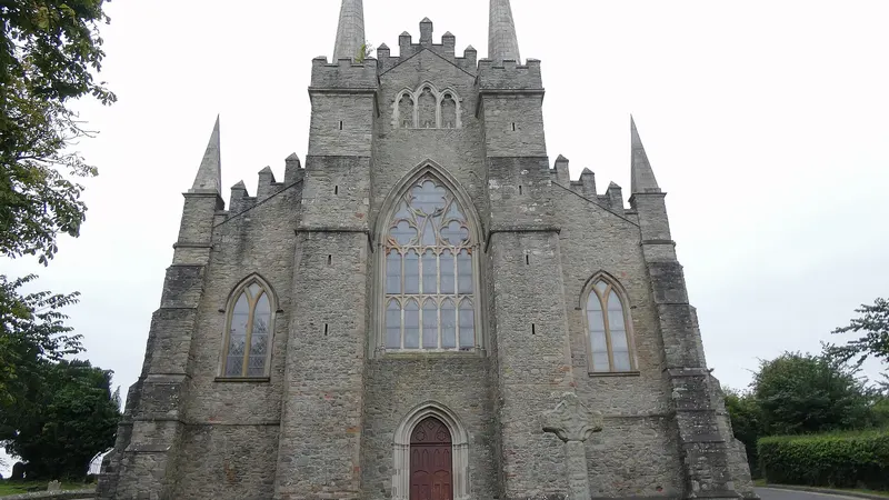 The grey stone west front of Down Cathedral with its pinnacles and a large pointed window
