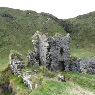 The ruined tower of Kinbane Castle on its grassy headland below the cliffs
