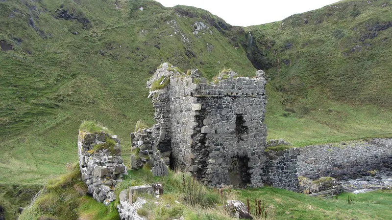The ruined tower of Kinbane Castle on its grassy headland below the cliffs